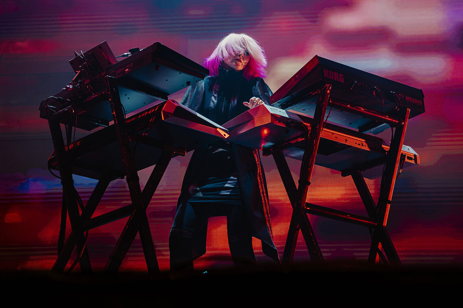 Keyboard player between keyboard stands in pink light, Faithless at Creamfields 2026