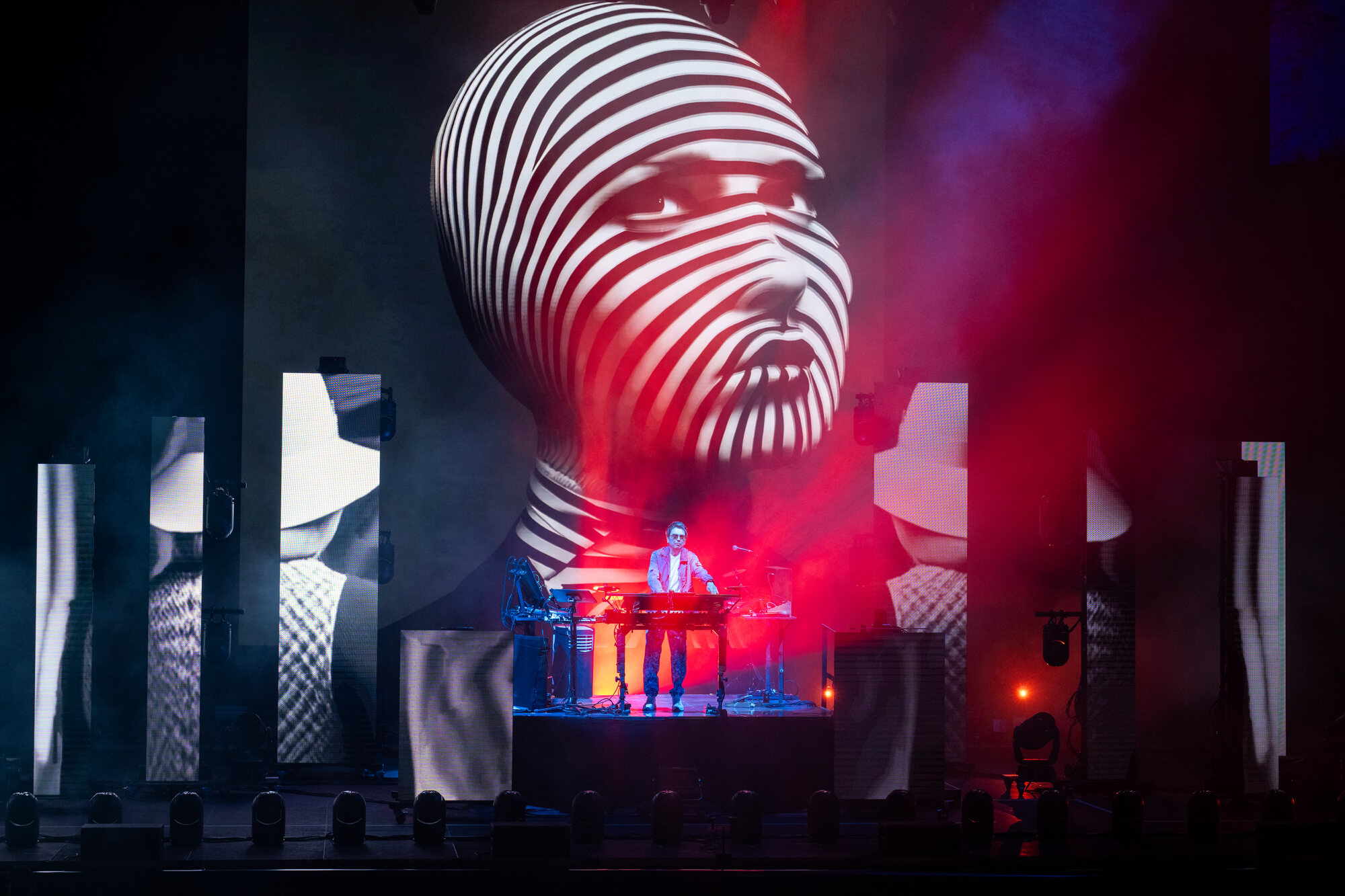 Striped video head above the stage in red haze